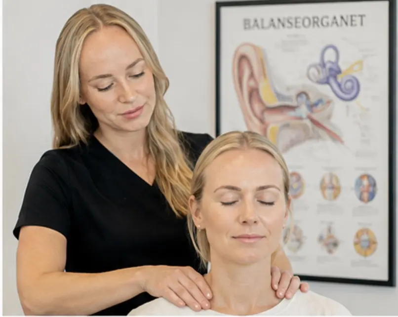 Kiropraktor Marie Hermansen undersøker nakken til en pasient foran en plakat av balanseorganet